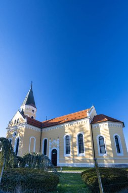 Güneşli bir günde parkta uzun ağaçlarla çevrili huzurlu bir kilise. Sahne, doğal ortamdaki rahatlama veya yansıma için mükemmel sakin, resim gibi bir ortam yakalar..