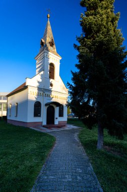 Bir parkın ortasında duran tuhaf bir şapel. Kapısına giden ağaçlık bir patika var. Huzurlu ortam, berrak mavi gökyüzü altında mimari ve doğanın ahenkli bir karışımıyla sükuneti taşır..