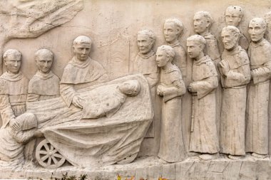 Tarihi bir bağlamda dini figürleri tasvir eden bir seremoni sahnesinin sergilendiği taştan yardım sanat eserleri, sanatsal temsil içinde giyimlerini ve ifadelerini vurguluyor. Tarih, sanat veya dinle ilgili projeler için harika.
