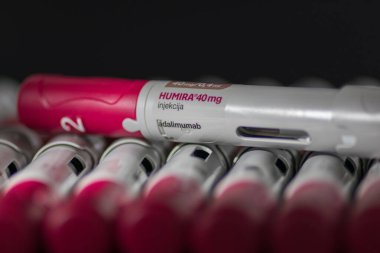 VINKOVCI, CROATIA, 05.26.2020: Humira enjeksiyon kalemleri ayrıntılı ve standart tasarımlarını canlı kırmızı ve beyaz renklerde göstererek düzenli bir şekilde sergilenmektedir. Tıbbi, sağlık hizmetleri veya ilaçla ilgili bağlamlar için ideal.