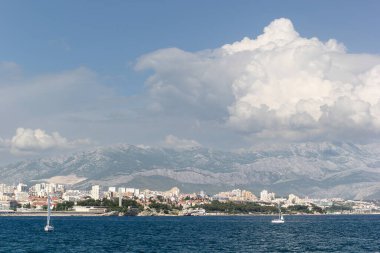 Split 'in deniz manzarası, tarihi işaretler, palmiye çizgili gezinti alanı ve berrak mavi gökyüzünün altındaki manzaralı dağ manzarası..