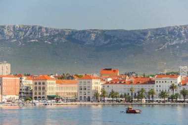Split 'in deniz manzarası, tarihi işaretler, palmiye çizgili gezinti alanı ve berrak mavi gökyüzünün altındaki manzaralı dağ manzarası..