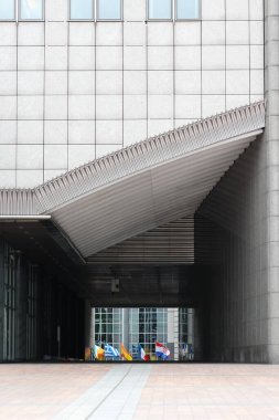 Küresel birlikteki tasarım estetiği ve sembolizmi vurgulayarak, geometrik cephenin altında uluslararası bayraklar sergilenen modern mimari özellikler.