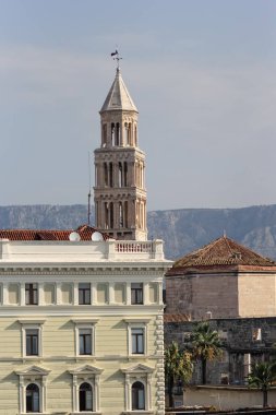 Büyüleyici tarihi mimariyle çevrili, sakin mavi gökyüzünün altındaki uzak bir dağ sırasına çarpıcı bir şekilde tasarlanmış çan kulesinin görüntüsü..