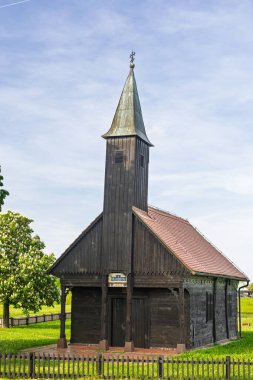 Geleneksel ahşap bir kilise binası. Uzun bir çan kulesi var. Etrafı çiçek açan çiçeklerle çevrili..