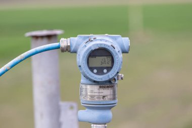 VINKOVCI, CROATIA, 03.23.2025: Çeşitli endüstrilerde açık havada bulanık bir arkaplanda net atmosfer basıncı okumalarını ölçmek ve görüntülemek için kullanılan dijital basınç sensörü.