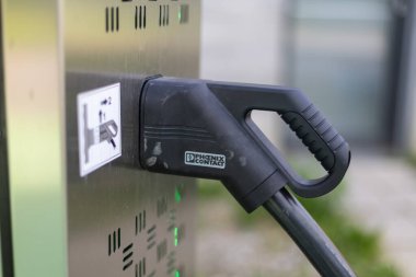 VELIKA GORICA, CROATIA, 04.23.2025: Sürdürülebilir ulaşım ve yenilenebilir enerjiyi sembolize ederek güvenli bir şekilde bir istasyona bağlı elektrikli bir araç. Kurulum, yenilik ve çevre sorumluluğunu vurgulayarak açık havada gerçekleşiyor..