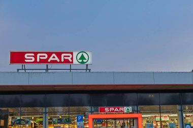 VELIKA GORICA, CROATIA, 04.22.2025: Alacakaranlıkta bir Spar marketinin dış görünüşü belirgin bir vitrin levhası ile. Temiz ve iyi aydınlatılmış bir alışveriş ortamı yakalar..