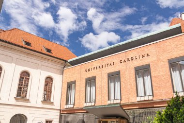 PRAGUE, CZECH REPUBLIC, 05.28.2022: Sahne, tarihsel önemi ve eğitici önemi vurgulanan canlı mavi gökyüzü altında klasik ve modern mimari tarzları gösteren ikonik bir üniversite cephesine sahiptir..
