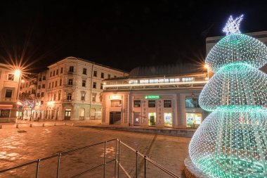 PULA, CROATIA, 01.06.2019: Kadim bir taş kemer ve yakınlardaki yapılar gece şenlikli dekorasyonlarla aydınlanarak büyülü bir tatil atmosferi ve çarpıcı mimari karşıtlıklar yaratıyor. Altın kapı, Pula..