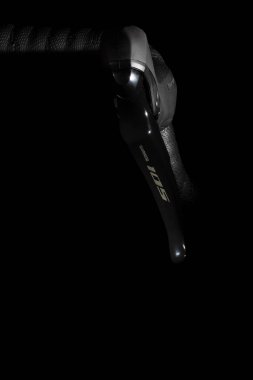 VINKOVCI, CROATIA, 12.06.2018: tasarımını ve mekaniklerini gösteren siyah bir arka plana karşı bisiklet fren kolunun detaylı yakın çekimi. Görüntü, bisiklet bileşenlerinin kalitesini ve hassasiyetini parlak bir estetikle vurgular..