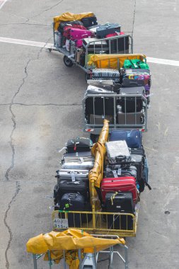 ALANA, TURKEY, 10.07.2018: Çeşitli bavullarla dolu paketli bagaj arabaları, havaalanı işlemleri ve bir pistte seyahat hazırlığı.