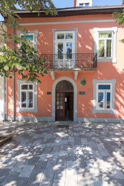 CETINJE, MONTENEGRO, 06.25.2019: Şeftali renkli bir binanın kemerli ahşap kapısının, geleneksel mimari detayları, dış ışık yansımaları ve gölgelere karşı kontrastlı, samimi ve davetkar bir ortam için.