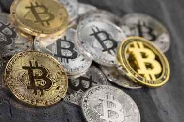 Kalıplı taş bir yüzeye yerleştirilmiş altın ve gümüş Bitcoin sikkelerinin düzenlenmesi, kripto para birimi ve dijital para birimi kavramlarını sembolize eder..