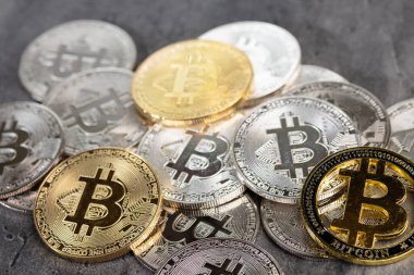 Kalıplı taş bir yüzeye yerleştirilmiş altın ve gümüş Bitcoin sikkelerinin düzenlenmesi, kripto para birimi ve dijital para birimi kavramlarını sembolize eder..