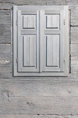 Kırsal ahşap duvar canlı bir dokuya ve kapalı panjurlara sahip büyüleyici basitliği ve ahşap işçiliğin zarafetini vurguluyor..