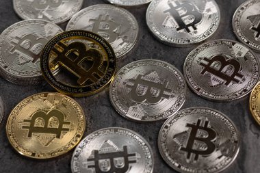 Kalıplı taş bir yüzeye yerleştirilmiş altın ve gümüş Bitcoin sikkelerinin düzenlenmesi, kripto para birimi ve dijital para birimi kavramlarını sembolize eder..