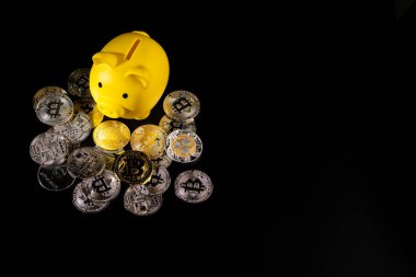 Siyah bir yüzey üzerinde gümüş ve altın Bitcoin paralarla çevrili sarı bir kumbara. Görüntü, modern teknoloji güdümlü bankacılık sektöründeki dijital para birimi, mali tasarruf ve yatırım stratejilerini sembolize ediyor..