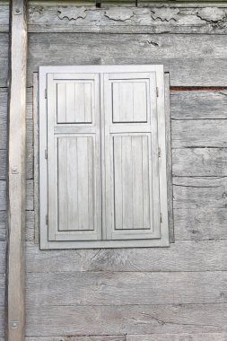 Kırsal ahşap duvar canlı bir dokuya ve kapalı panjurlara sahip büyüleyici basitliği ve ahşap işçiliğin zarafetini vurguluyor..