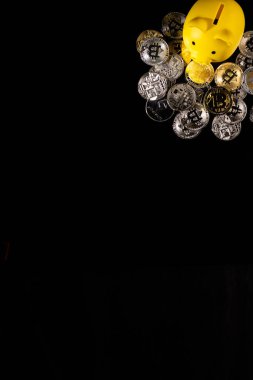 Siyah bir yüzey üzerinde gümüş ve altın Bitcoin paralarla çevrili sarı bir kumbara. Görüntü, modern teknoloji güdümlü bankacılık sektöründeki dijital para birimi, mali tasarruf ve yatırım stratejilerini sembolize ediyor..