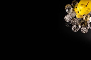 Siyah bir yüzey üzerinde gümüş ve altın Bitcoin paralarla çevrili sarı bir kumbara. Görüntü, modern teknoloji güdümlü bankacılık sektöründeki dijital para birimi, mali tasarruf ve yatırım stratejilerini sembolize ediyor..