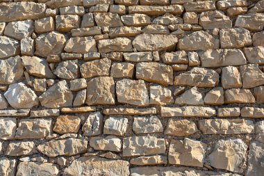 A close-up view of a stacked gray stone wall built from irregularly shaped rocks. Natural texture and rugged craft convey rustic charm, durability, and traditional masonry work suitable for architecture and outdoor decor.