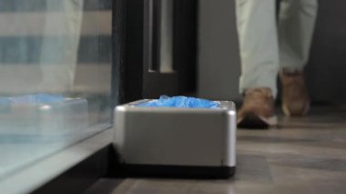 Otomatik bot kapağı giydirme aracı, kahverengi ayakkabılı bir adam bot kılıfı giyer, mekanik tampon..