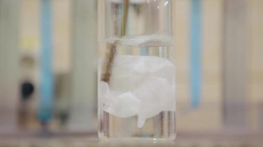 Kağıt kesiği bir şişe suya atılmış ve karıştırılarak eritilmiş. Yakın plan.