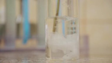 Kağıt kesiği bir şişe suya atılmış ve karıştırılarak eritilmiş. Yakın plan.