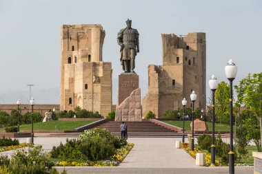 SHAHRISABZ, UZBEKISTAN - APRIL 16, 2022: Statue of Amir Temur and heritage twin buildings in Ak-Saray Palace, Shahrisabz, Uzbekistan clipart