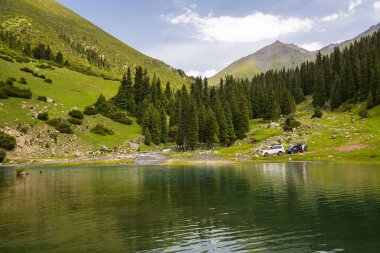 Kırgızistan, Orta Asya 'daki Tianshan Dağları' ndaki köknar ağaçları arasındaki turkuaz göl manzarası