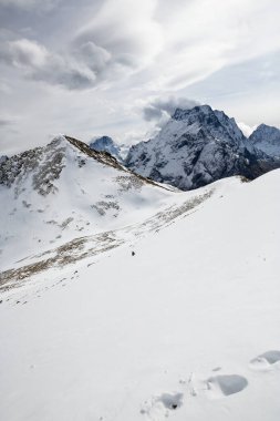 Kayak merkezi Dombay, Karachay-Cherkessia Republic, Rusya 'da yüksek karlı dağların bulutlu gökyüzüne bakan görüntüsü
