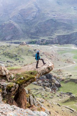 KABARDINO-BALKARIA, RUSSIA - 17 Ekim 2022: Kafkasya 'daki Cherek vadisinin arka planında Trol dilinde duran kadın turist görüntüsü