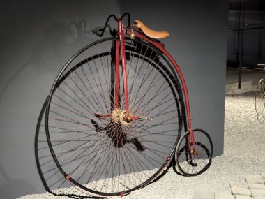 Klasik yüksek tekerlekli bisiklet. Kırmızı yüksek tekerlekli bisiklet, ayrıca bir peni-peni olarak da bilinir, büyük bir ön tekerleği ve çok daha küçük bir arka tekerleği vardır.. 