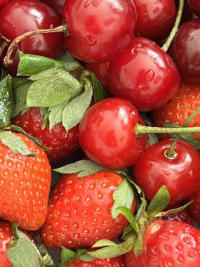 Kiraz ve çilek sosu. Sulu kırmızı kirazlar ve çilekler yakından paketlenmiştir. Canlı ve taze görünümlerini vurgularlar.. 