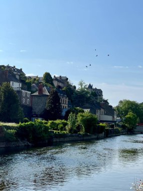 Fransa 'nın Normandiya şehrinde küçük bir kasaba. Tepenin yamacında eğimli çatıları olan geleneksel taş evlerin yer aldığı büyüleyici küçük kasaba manzarası. Önplanda sakin bir nehir akıyor.