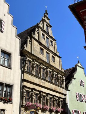 Almanya 'nın Rothenburg ob der Tauber kentindeki eski binalar. Cobblestone caddesi, sarp gabaylı çatıları ve pastel cepheleri olan geleneksel yarı keresteli binalarla doludur.. 