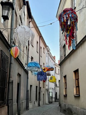 Lublin, Polonya 'nın tarihi merkezi. Tarihi binalarla kaplı dar kaldırım taşı sokakta yukarıda asılı renkli ve tuhaf süslemeler var.. 