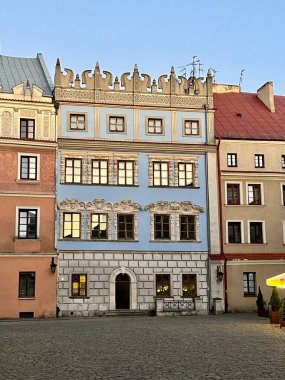 Lublin Pazar Meydanı, Polonya. Renkli binaların tarihi sıraları. Merkezi yapı, karmaşık dekoratif kalıplara sahip açık mavi bir cephe ve yontulmuş detaylara sahip bir parapet içerir.. 