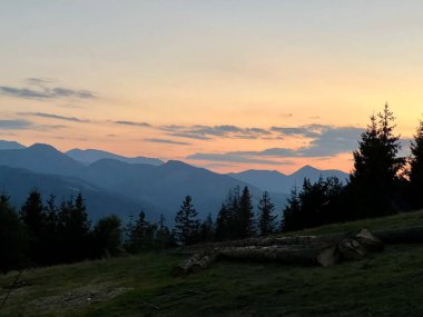 Tatra dağlarında gün batımı, Zakopane, Polonya. Karanlık, sivri dağ siluetleri yumuşak portakallar ve mavilerden oluşan solgun bir gökyüzüne karşı yükseliyor.. 