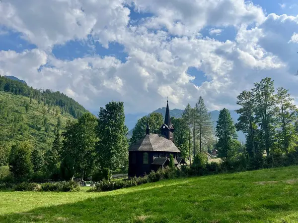 Slovakya 'nın Tatranska Javorina kentindeki kilisenin ve Tatra dağlarının çarpıcı panoramik manzarası. Yoğun orman ve yuvarlanan tepelerle çevrili yemyeşil vadide yuva yapmış ahşap kilise.