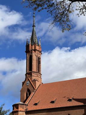 Saint Mary Kilisesi, Druskininkai, Litvanya kırmızı tuğlalı kilise kulesi ve üzerinde haç bulunan sivri uçlu bir kule. Yapı kemerli pencereler ve dekoratif kuleler var. 