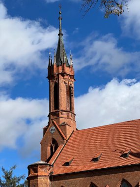 Saint Mary Kilisesi, Druskininkai, Litvanya kırmızı tuğlalı kilise kulesi ve üzerinde haç bulunan sivri uçlu bir kule. Yapı kemerli pencereler ve dekoratif kuleler var. 