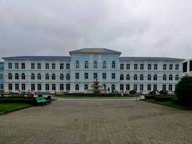 Batumi Shota Rustaveli Devlet Üniversitesi binası simetrik perdeli ve beyaz dekoratif pervazlarla çevrili soluk mavi duvarlı Neoklasik tarzda bir bina.. 