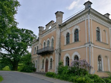 Büyük tarihi Glitiskes malikanesi bej, sıva dış görünüşlü, kemerli pencereler ve dekoratif pervazlarla süslenmiş. İkinci katta dövülmüş demir bir balkon olduğu sanılıyor. Litvanya 