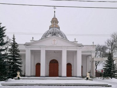 Daugavpils 'deki Aziz Peter-in-Chains Katolik Kilisesi belirgin beyaz cephesi ve merkezi kubbesi olan Neoklasik Kilisesi. Girişi destekleyen dört büyük kolon var. Kar zemini kaplıyor. 