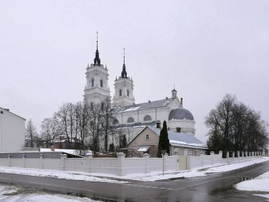 Daugavpils 'deki kusursuz Katolik Kilisesi karlı bir manzarada Barok tarzı bir kilise ve tepesinde kuleler olan iki uzun kule. Ön cephe beyaz ve kemerli pencereler var.. 