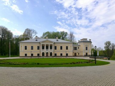 Litvanya 'daki Jasiunai malikanesi. Soluk sarı ve beyaz tonlara sahip neoklasik mimarisi olan tarihi malikane. Binanın dikdörtgen pencereleri ve çatıda dekoratif balyaları var..
