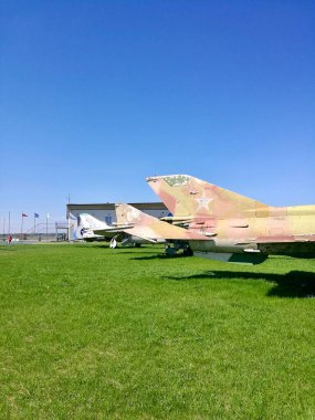 Panevezys Istra Havaalanı. Açık mavi gökyüzünün altında, çimenli bir alanda klasik askeri uçaklar sergileniyor.. 