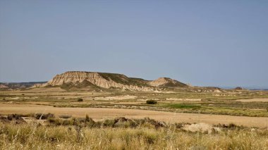 Navarre, İspanya 'daki yarı çöl Bardenas Reales' in panoramik manzarası. Özellikler arasında kil, tebeşir ve kumtaşından oluşan aşınmış tepeler ve kayaların katmanlı katmanlarını göstermesi yer alıyor.. 